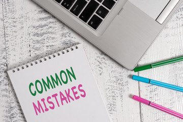 Word writing text Common Mistakes. Business photo showcasing actions that are often used interchangeably with error Top trendy metallic laptop blank spiral notepad pens lying wooden table