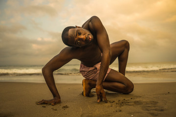 dramatic contemporary dance choreographer doing ballet beach workout, young attractive and athletic afro black American man dancing on sunrise