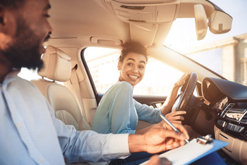 Happy woman in examination car, smiling to male instructor