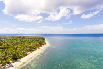 Fototapeta na wymiar Seascape, coast of the island of Siargao, Philippines. Blue sea with waves and sky with big clouds, top view.
