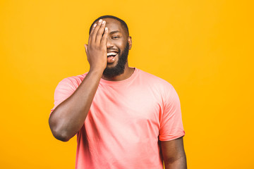 Portrait of a cheerful young african man standing against yellow background.