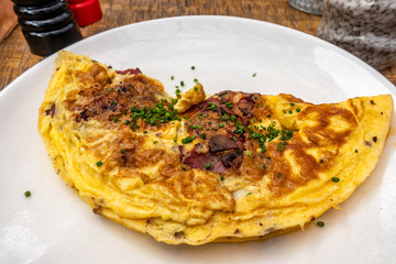 Breakfast food - Omelette with meat, cheese, onion on the white plate
