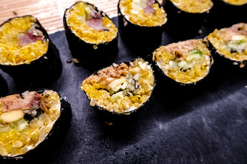 Healthy homemade sushi rolls with brown rice, fish and green vegetable rolls.
