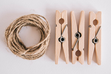 Wooden clothespins with rope on white background. View from above. Copy space