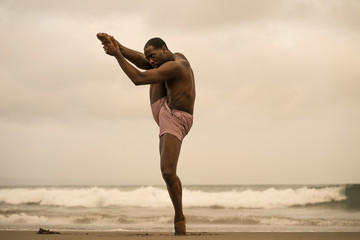 Fototapeta na wymiar dramatic contemporary dance choreographer doing ballet beach workout, young attractive and athletic afro black American man dancing on sunrise