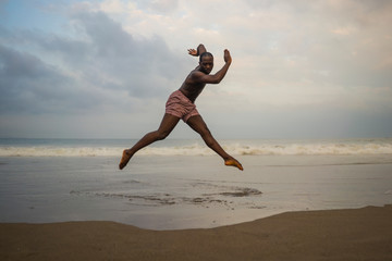 Fototapeta na wymiar dramatic contemporary dance choreographer doing ballet beach workout . young attractive and athletic afro black American man dancing on sunrise jumping