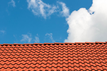 Red tiles on rooftop, beautiful blue sky with white clouds in the background.