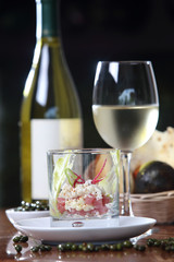 Cocktail of tuna, avocado, capers and chili accompanied by a glass of white wine.