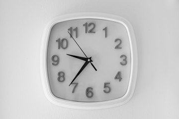 White clock hanging at the wall. black and white background
