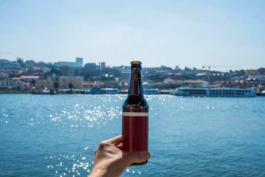 Man hand holding beer outdoors in European Summer - Porto Portugal