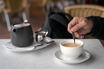 Stirring cup of coffee with a spoon.