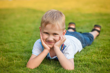 Portrait of a smiling boy lying on green grass.