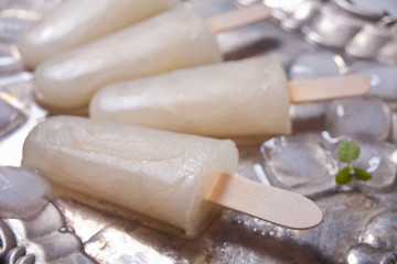 Homemade melon popsicles with ice against a vintage metal tray background