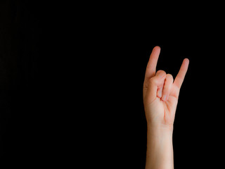 Hand with horns sign on black background with copy space