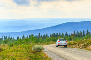 Fototapeta premium Car on a dirt road in a high country landscape view
