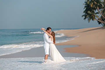 Fototapeta na wymiar Summer holidays, people, love, travel and dating concept . Happy just married couple hugs and kiss over tropical beach background. Concept marriage, just married