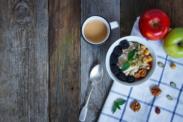 Top view oatmeal porridge, coffee, apple, berries and nuts on a wooden table, selective focus