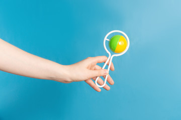 Woman holds baby rattle on blue background. Space for text