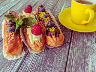 Still life with sweets eclairs with fruits on the wooden background