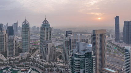 Fototapeta premium Aerial top view of Dubai Marina night to day timelapse. Modern towers and traffic on the road