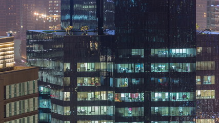 Lights in windows of modern multiple story office building in urban setting at night timelapse