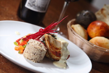 Roast chicken served with risotto and fresh vegetables with red wine.