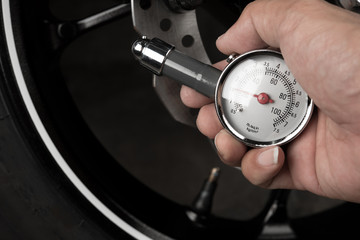 Hand of man show gauge measurement pressure 22 psi , checking tire