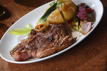 T-bone steak grilled beef with red and green peppers and baked potato.