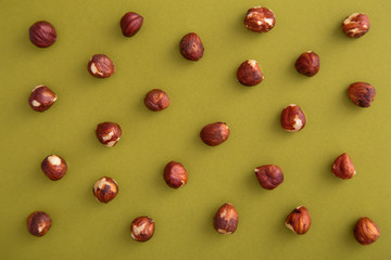 Hazelnuts pattern on a green background viewed from above. Nuts creative layout. Top view
