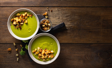 Bowl of cream broccoli soup with bread croutons on a wooden background