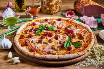 Delicious pizza with olives and sausages on wooden table.