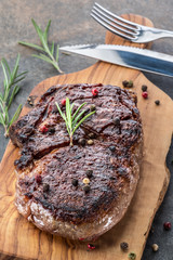 Medium rare Ribeye steak with herbs and a piece of butter on the wooden tray.