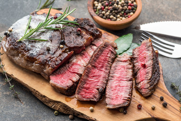 Medium rare Ribeye steak with herbs and a piece of butter on the wooden tray.