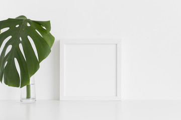 White square frame mockup with a monstera leaf in a vase on a white table.