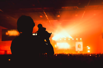 silhouette camera man standing record live concert with smoke and light performance background