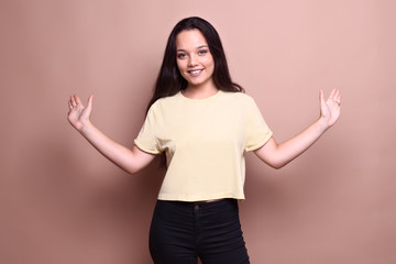 cheerful beautiful brunette girl in front of a brown background gestures with her arms