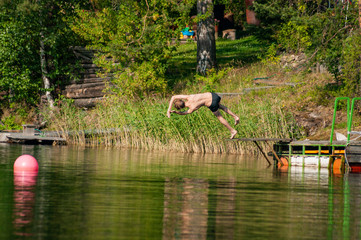 Fototapeta na wymiar man jumping into the lake on a hot summer day