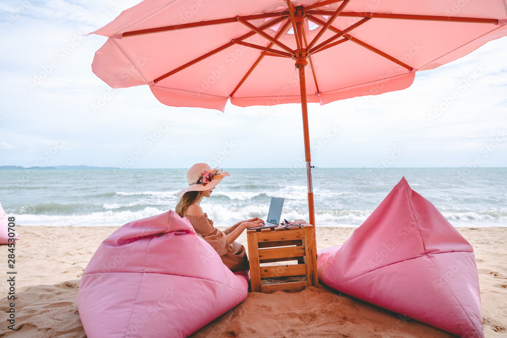 Wall mural woman with laptop in cafe on beach