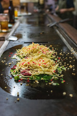 Okonomiyaki, Japanese pancake in the making. Tasty traditional dish from Hiroshima prefecture, Japan.