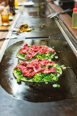 Okonomiyaki, Japanese pancake in the making. Tasty traditional dish from Hiroshima prefecture, Japan.