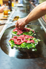 Okonomiyaki, Japanese pancake in the making. Tasty traditional dish from Hiroshima prefecture, Japan.