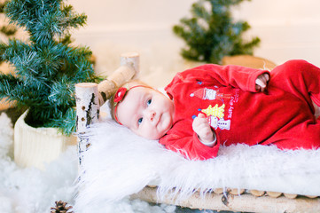 Obraz na płótnie Canvas Cute newborn baby in a Christmas costume on a wooden bed in Christmas decorations