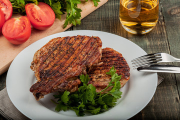 a piece of fried pork with herbs on a white dish on a wooden table, closeup view