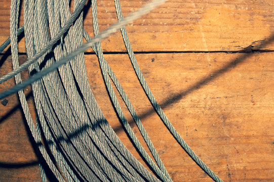 Steel Cable On Wooden Table. Hank Of Metal Rope Close Up