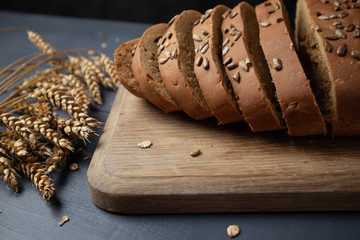 Sliced ​​whole grain bread on a board with spikelets of wheat