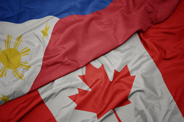 waving colorful flag of canada and national flag of philippines.