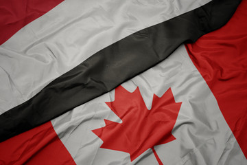 waving colorful flag of canada and national flag of yemen.