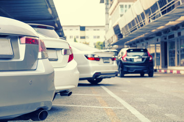 Car parked at indoor parking line with car running in back.