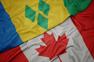 waving colorful flag of canada and national flag of saint vincent and the grenadines.
