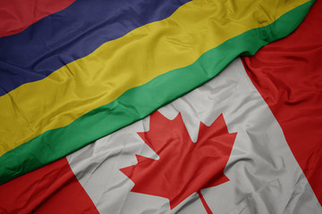 waving colorful flag of canada and national flag of mauritius.